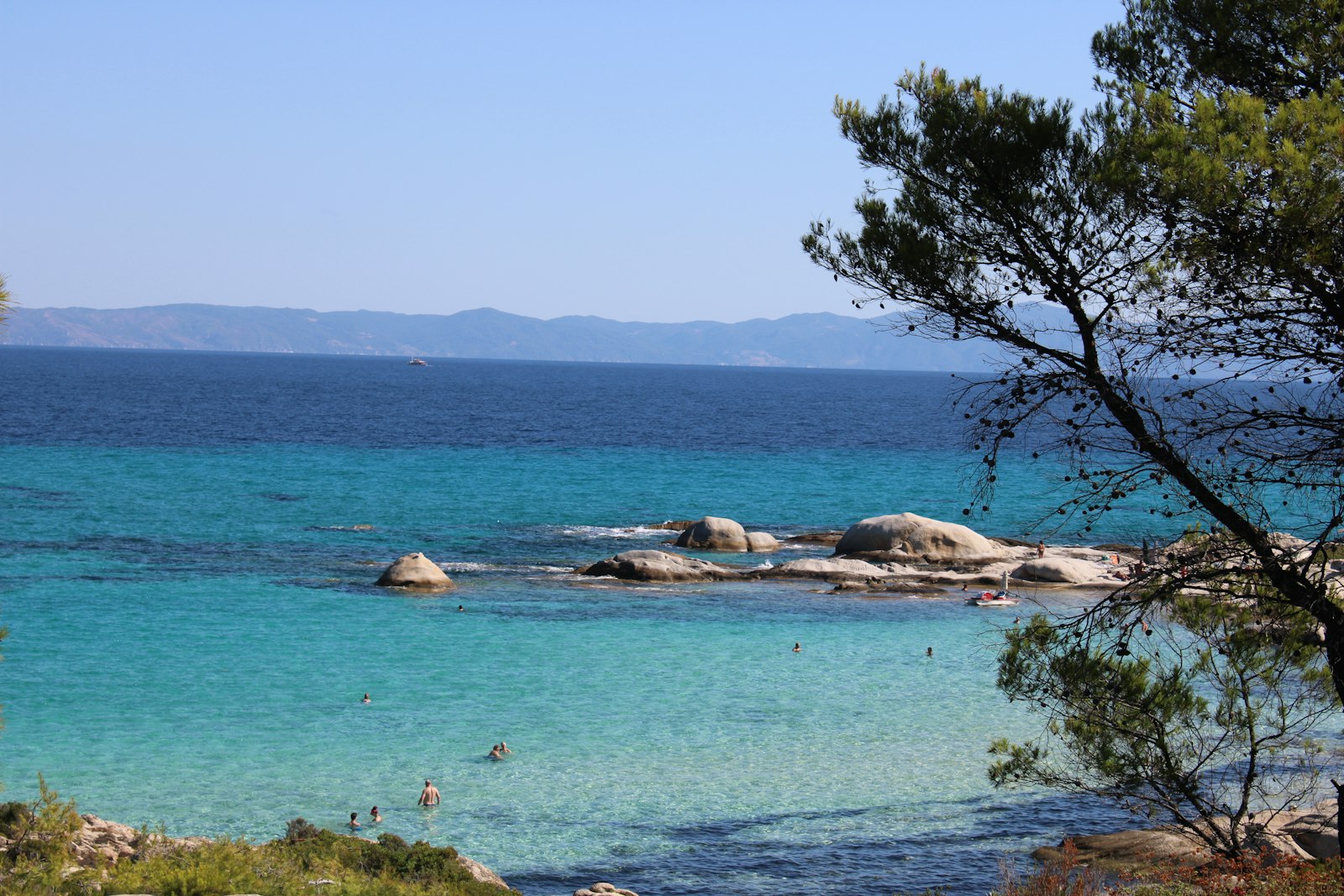 Turquoise zwemplek met rotsen en pijnbomen aan de kust bij Thessaloniki
